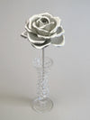 Leafless silver crepe paper rose standing in a slender glass vase
