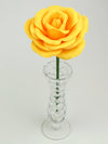Leafless yellow paper rose standing in a slender glass vase